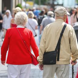 Ein älteres Paar geht zum Einkaufen durch eine Innenstadt. 