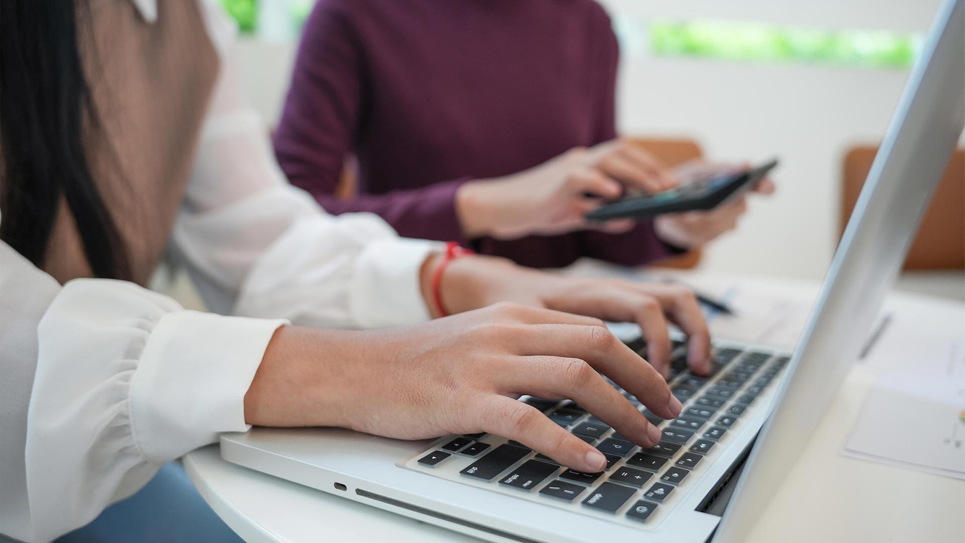 Zwei Personen an Laptop und Tablet in einem Büro. | picture alliance / Zoonar