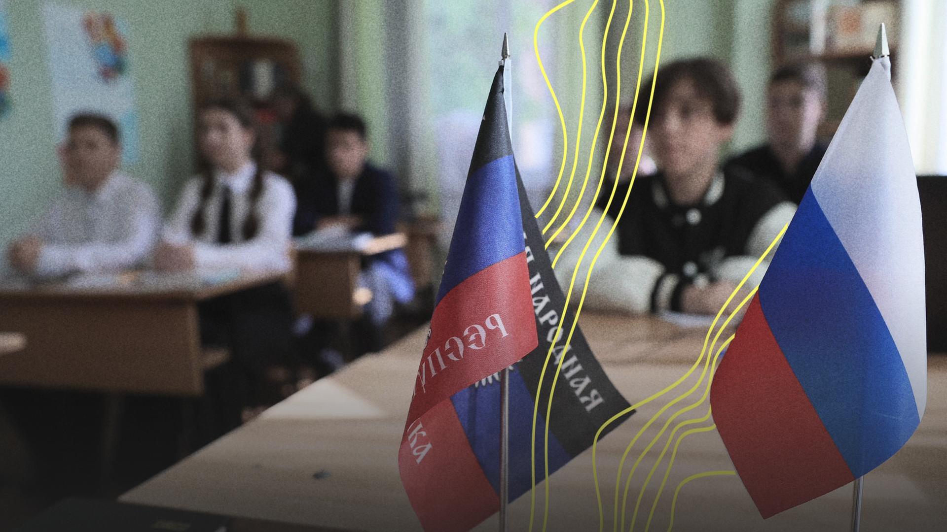 Auf dem Schreibtisch einer Schule stehen die Flaggen der von Russland sogenannten Volksrepublik Donezk und Russlands. | picture alliance/dpa/TASS | Dmitry Yagodkin