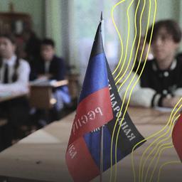 Auf dem Schreibtisch einer Schule stehen die Flaggen der von Russland sogenannten Volksrepublik Donezk und Russlands.
