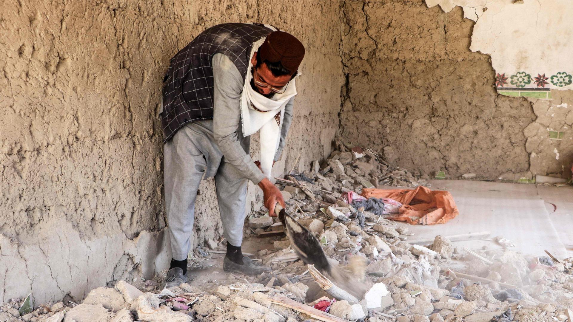 Ein Mann räumt nach einem pakistanischen Angriff auf die afghanische Region Paktika Schutt auf. | AFP