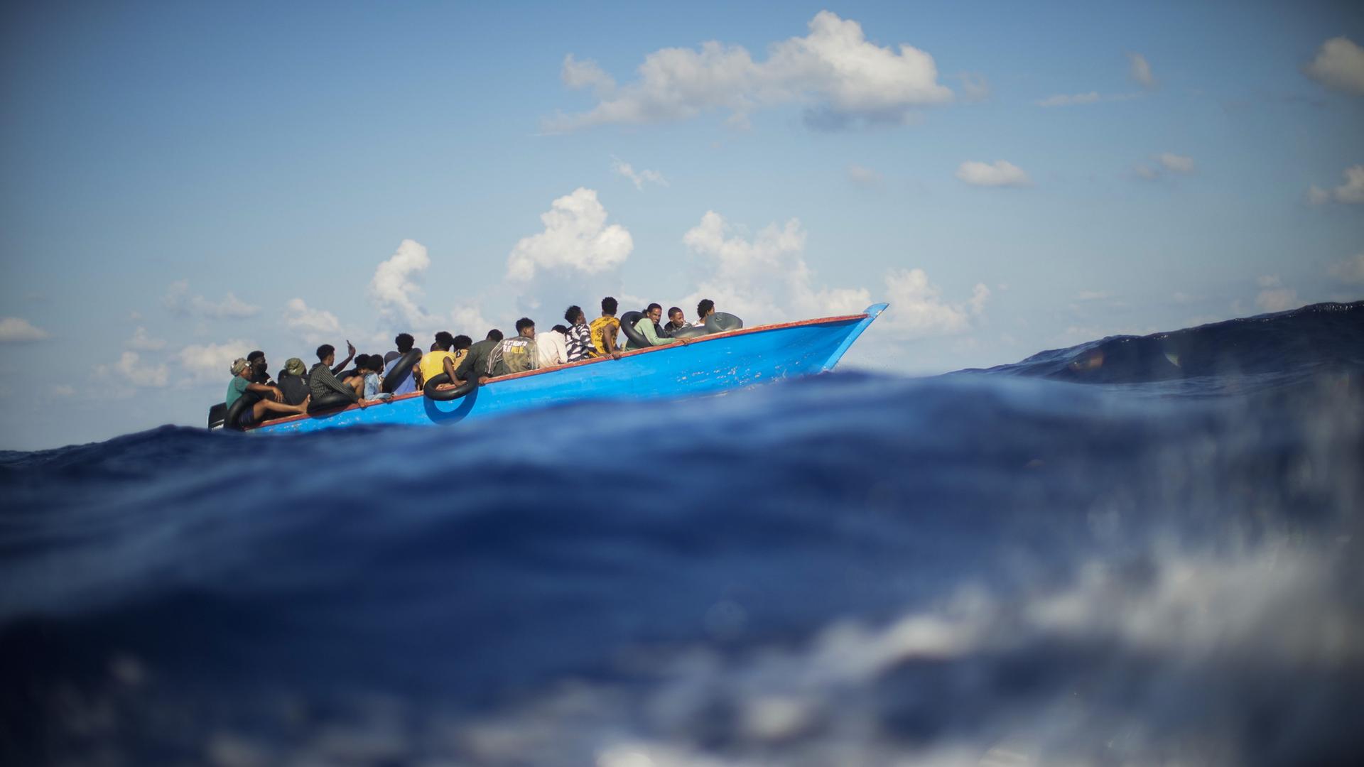 Migranten sitzen in einem Holzboot im Mittelmeer. (Archivbild: 11.08.2022) | Francisco Seco/AP/dpa