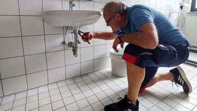 Ein Mann installliert ein Abflussrohr.