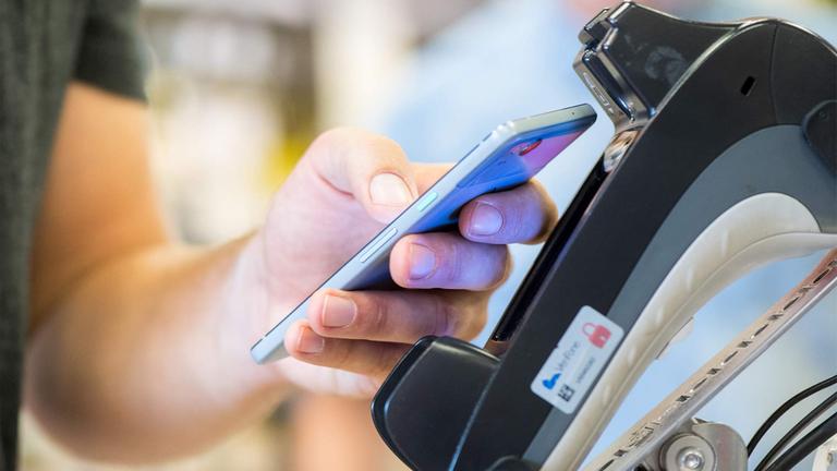 Ein Smartphone wird an einen Bezahl-Terminal gehalten.