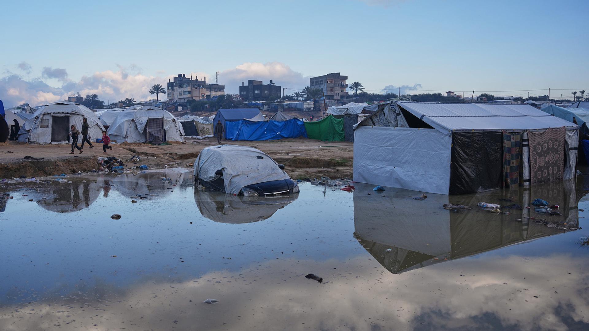 Palästinensische Kinder laufen in Zawaida nach starken Regenfällen an einer Schlammpfütze vorbei. | AP