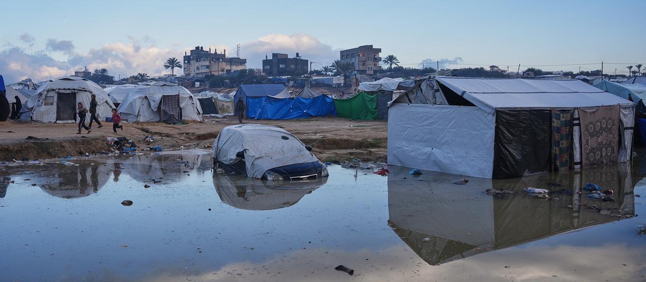 Palästinensische Kinder laufen in Zawaida nach starken Regenfällen an einer Schlammpfütze vorbei.