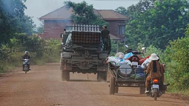 Menschen fahren mit Rollern und Transportwagen hinter einem Militärfahrzeug zur Evakuierung in Kambodscha, in der Provinz Oddar Meanchey. 