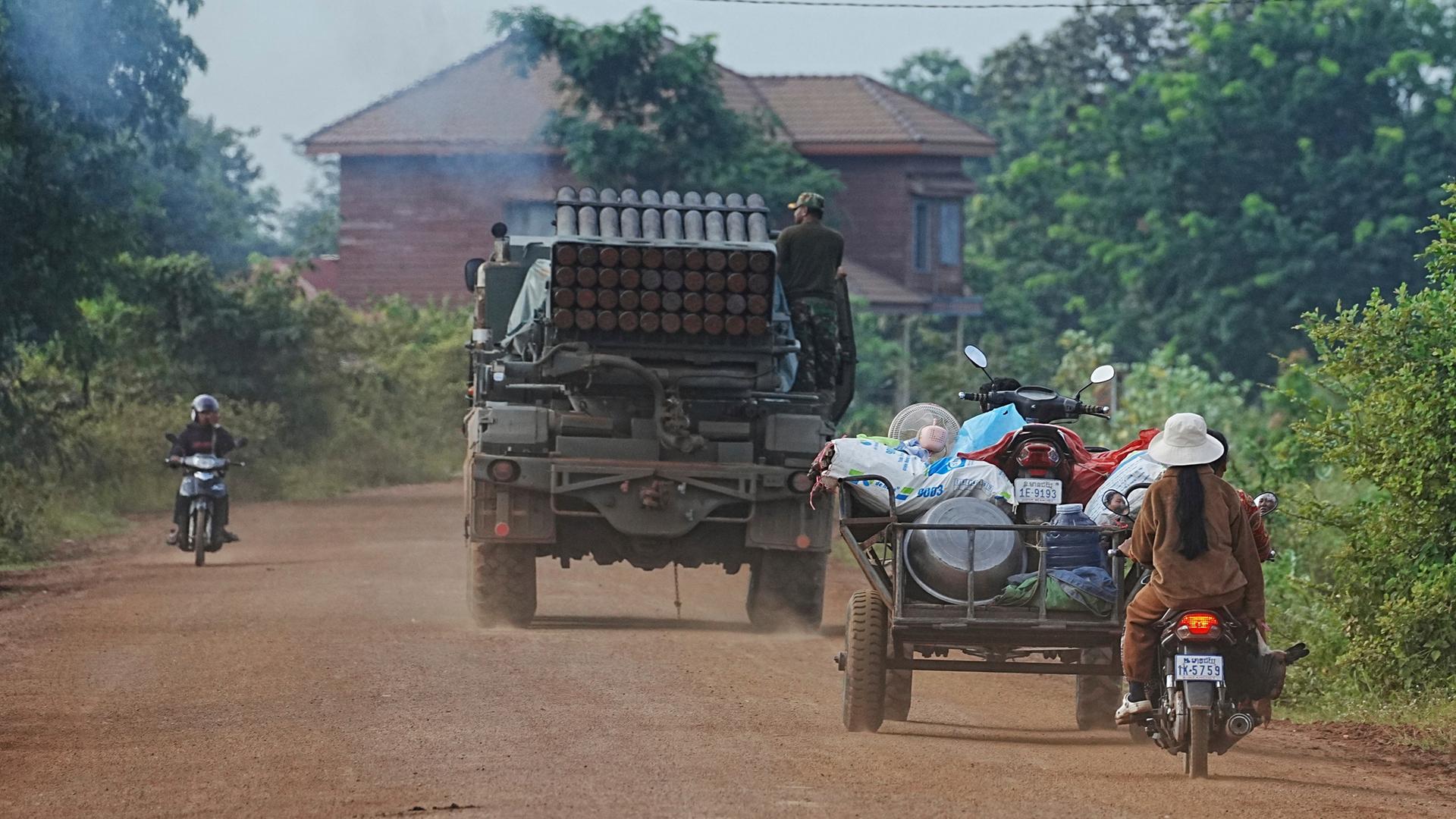 Menschen fahren mit Rollern und Transportwagen hinter einem Militärfahrzeug zur Evakuierung in Kambodscha, in der Provinz Oddar Meanchey.  | dpa