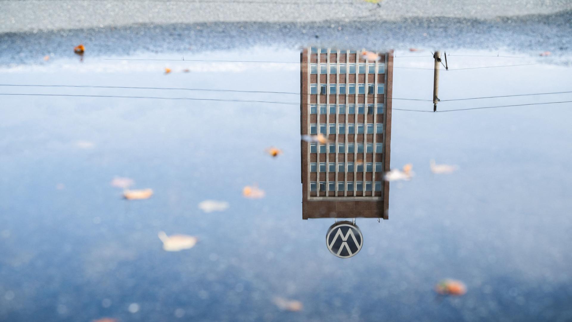 Das Markenhochhaus am VW-Stammwerk in Wolfsburg spiegelt sich in einer Pfütze.  | Julian Stratenschulte/dpa