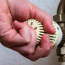 Eine Hand umschließt einen Thermostat