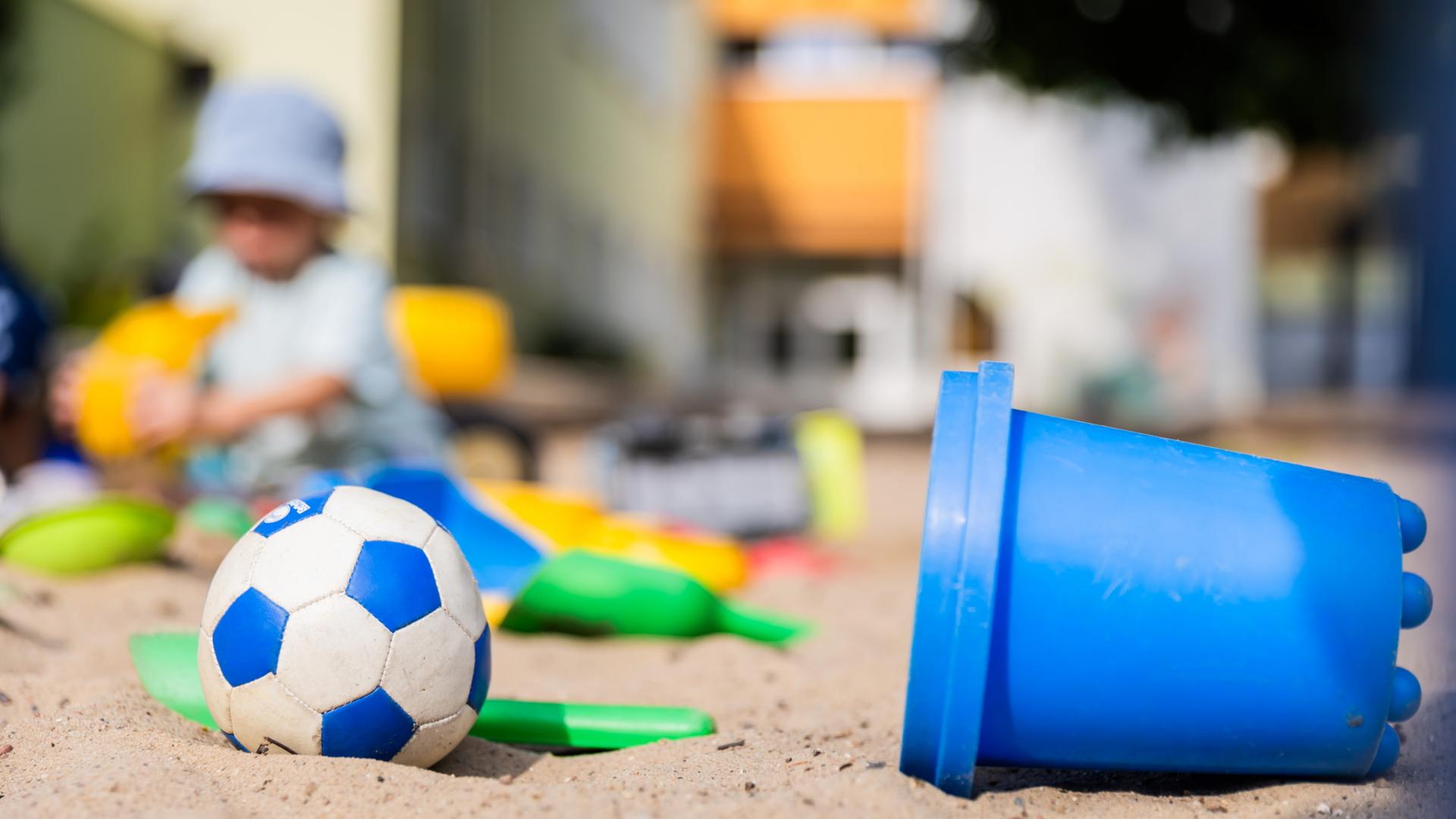 Ein Kind spielt im Sandkasten einer Kita.
