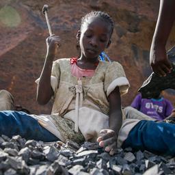 Ein Kind bricht mit einem Hammer Steine in Nairobi.