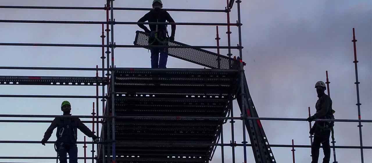 Silhouetten von Arbeitern beim Gerüstbau.