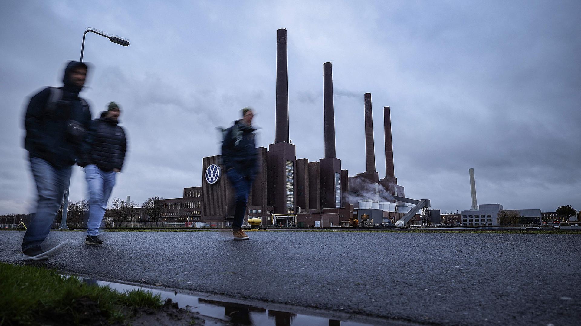 Arbeiter gehen über das VW-Gelände in Wolfsburg. | AFP