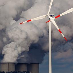 Windräder drehen sich vor den Kühltürmen eines Braunkohlekraftwerks.