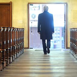 Mann verlässt eine Kirche mit Holzbänken