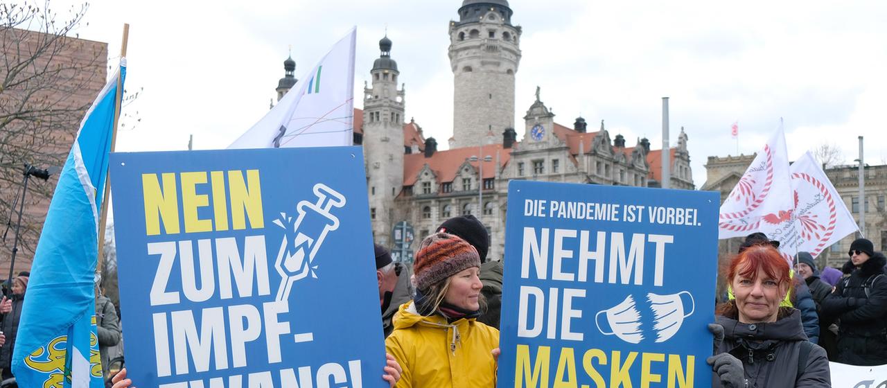 Teilnehmerinnen einer Demonstration von Gegnern der Coronamaßnahmen der Bundesregierung in Leipzig halten Schilder mit der Aufschrift "Nein zum Impfzwang" und "Nehmt die Masken ab".