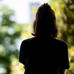 Ein Mädchen steht am Fenster und schaut raus.