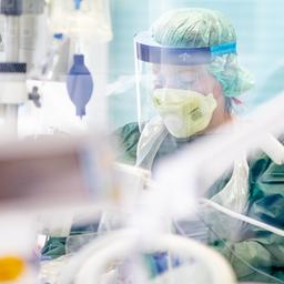 Eine Krankenpflegerin arbeitet in in Schutzkleidung in einem Krankenzimmer auf der Intensivstation des Uniklinikums Essen