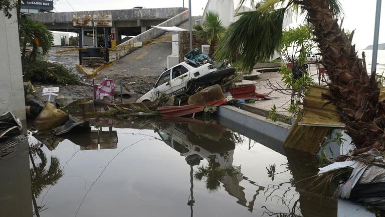 Trümmer und ein Autowracks liegen auf den durch den Hurrikan "Otis" verwüsteten Straßen in Acapulco.
