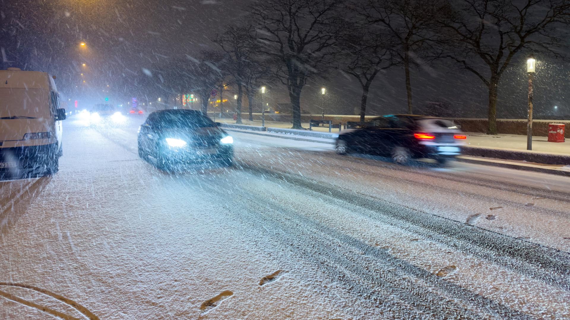 Schnee fällt am späten Abend auf einer Straße am Hafen in Hamburg. | dpa