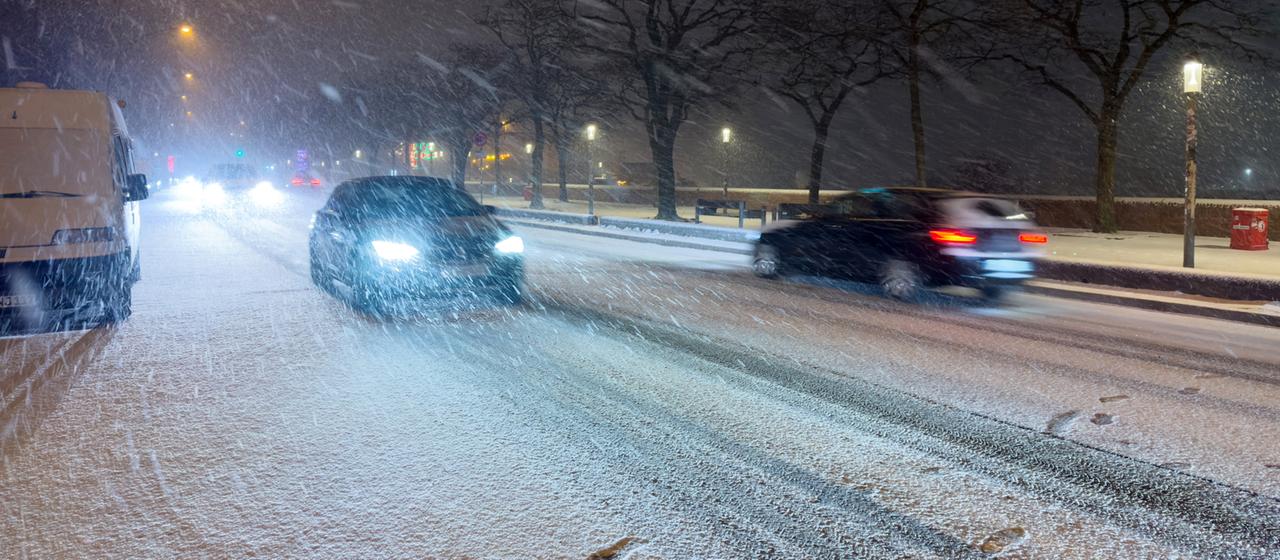 Schnee fällt am späten Abend auf einer Straße am Hafen in Hamburg.