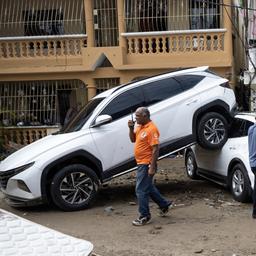 Menschen laufen an aufeinander aufgetürmten Autos in der Dominikanischen Republik vorbei.