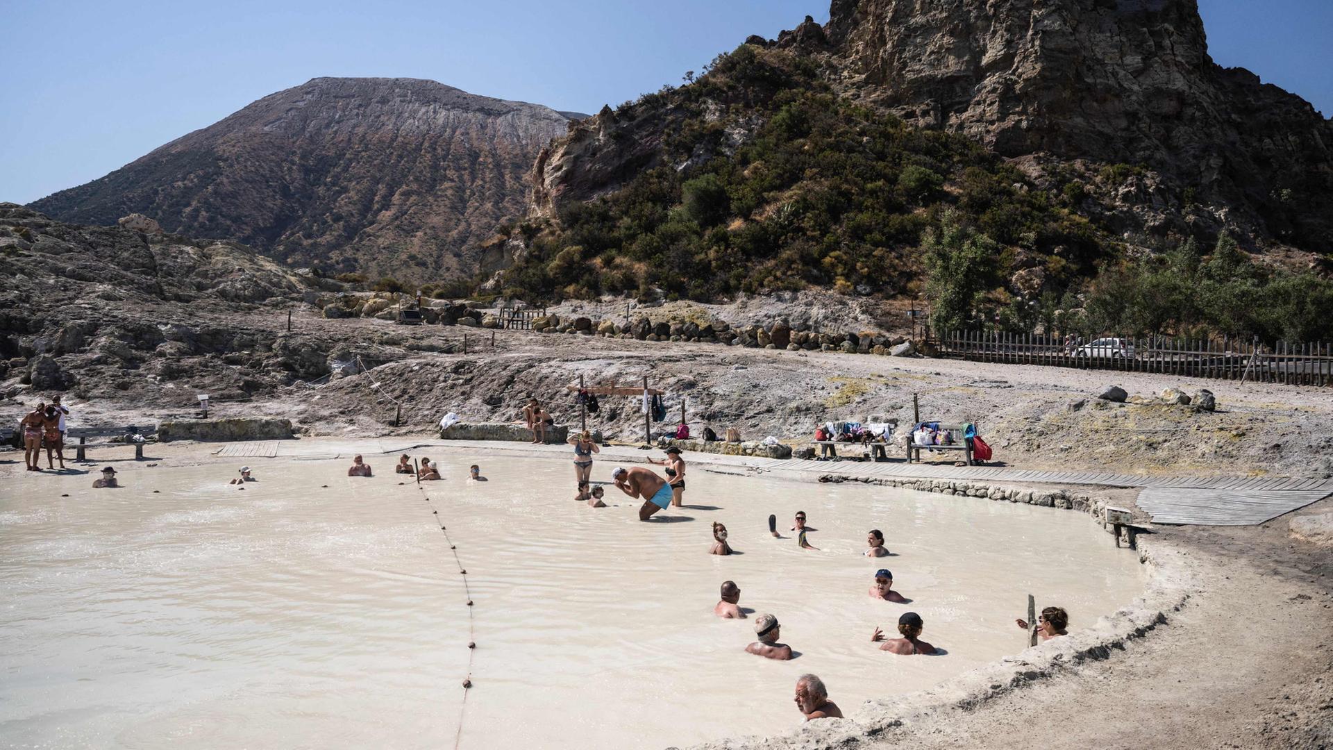 Menschen tauchen in das natÃ¼rliche Thermalschlammbecken auf der Insel Vulcano ein. | AFP