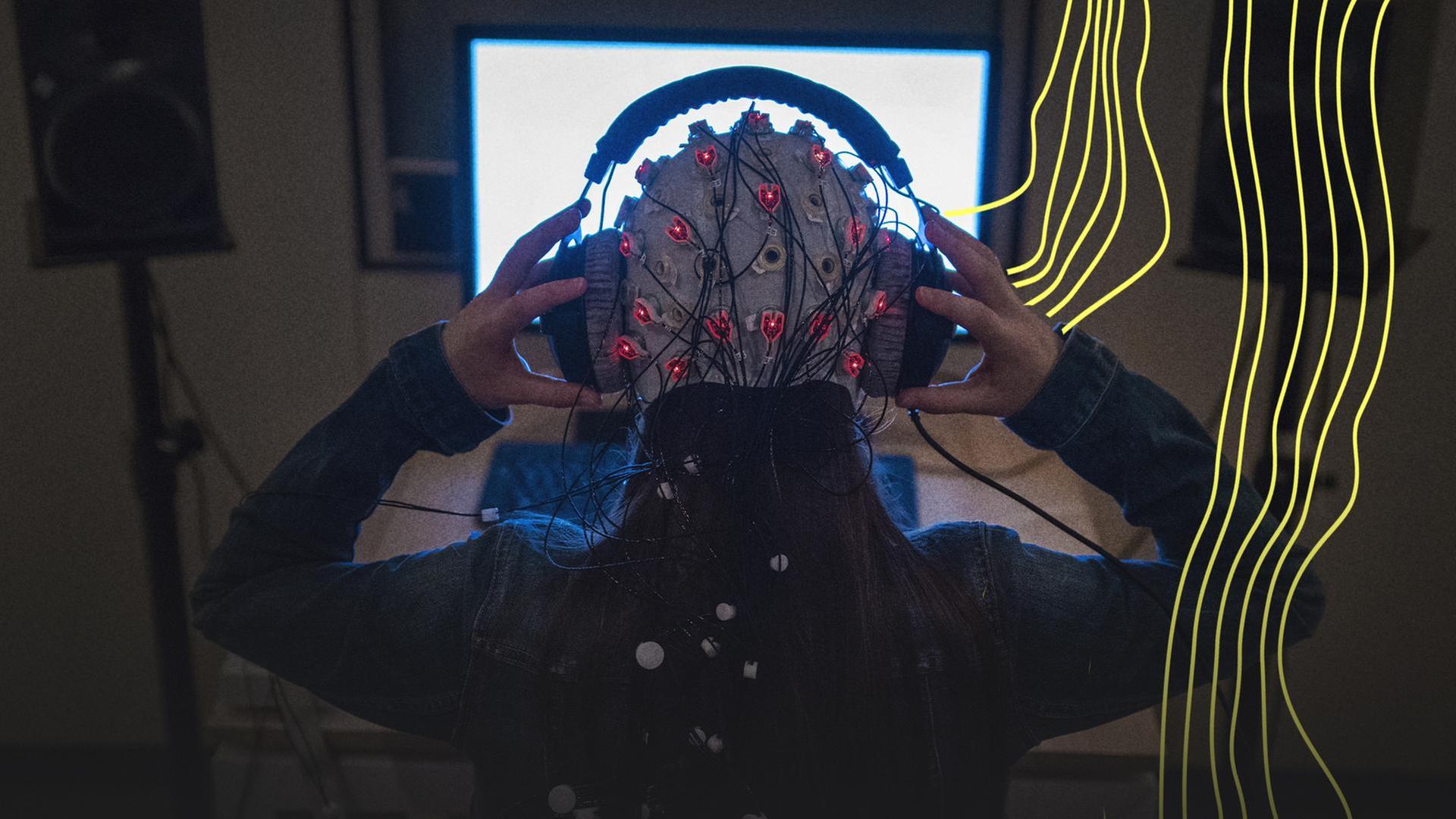 Die studentische Hilfskraft setzt sich zu Demonstrationszwecken einen KopfhÃ¶rer auf eine Kappe mit Elektroden zur Messung von Hirn-AktivitÃ¤t am 12.08.2016 in Frankfurt/M. (Hessen) auf. | picture alliance / dpa, Andreas Arnold