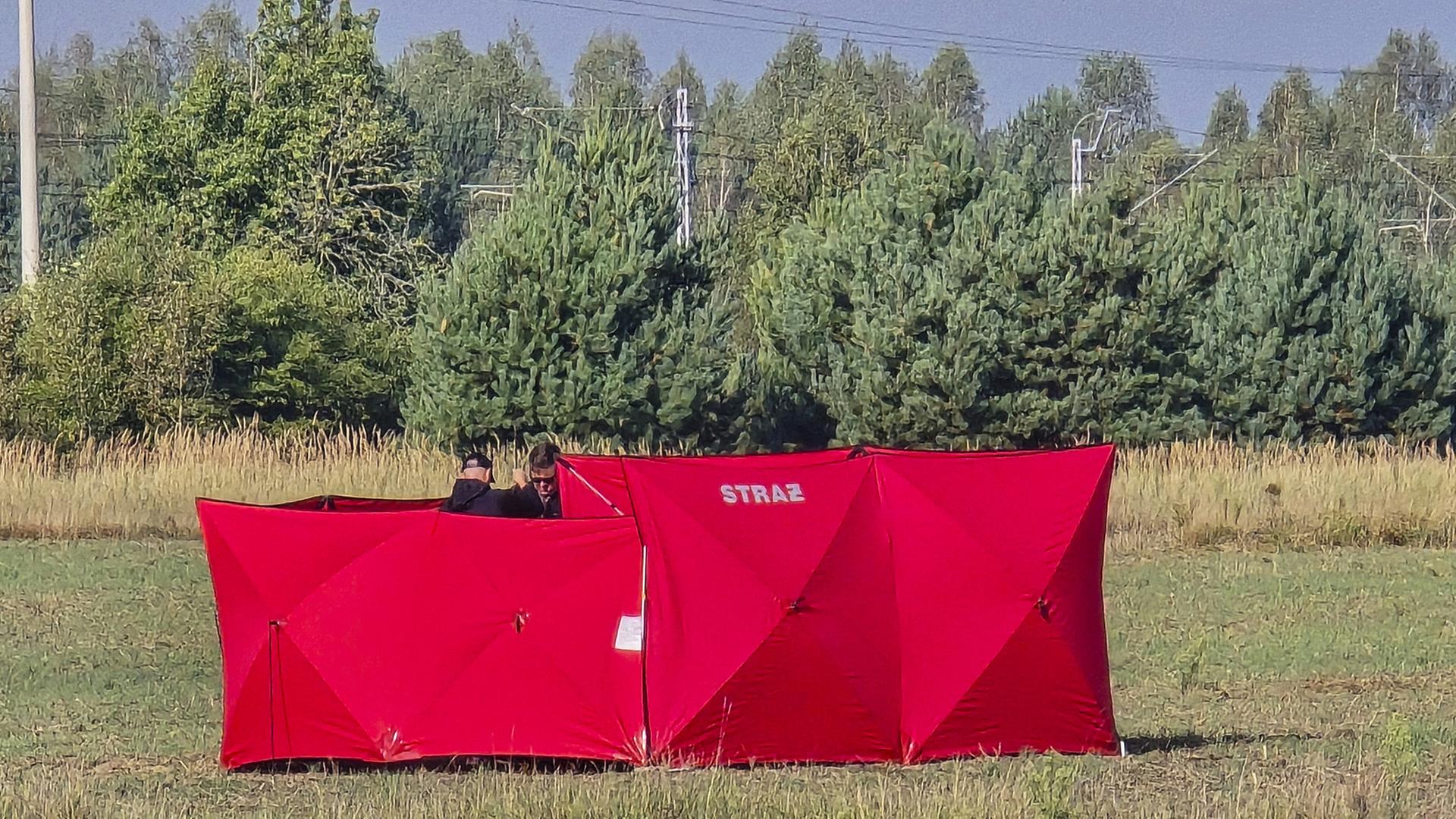 Feuerwehrleute sichern Teile einer beschädigten, von polnischen Behörden abgeschossenen Drohne auf einem Gelände in Czosnówka in der Nähe von Biala Podlaska. | dpa