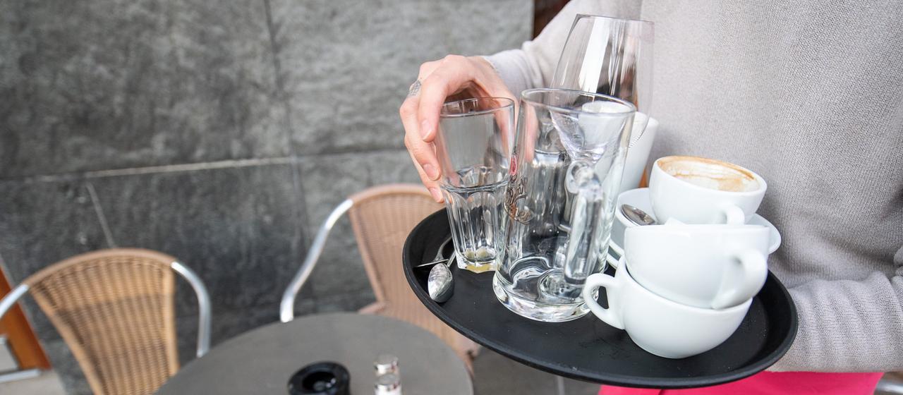 Ein Kellner räumt Geschirr in einem Café ab