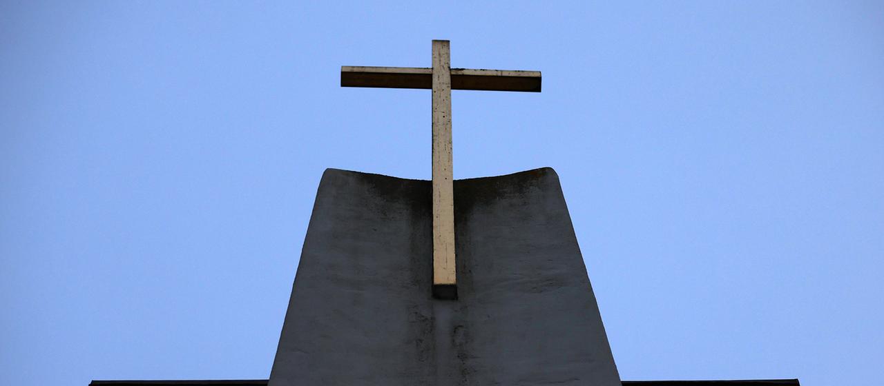 Ein Kreuz ist an der Fassade einer Kirche zu sehen.
