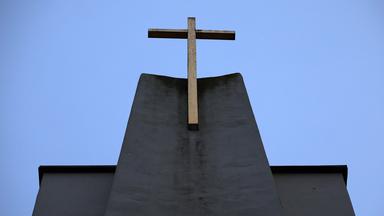 Ein Kreuz ist an der Fassade einer Kirche zu sehen.