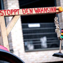 An einem Traktor ist bei einer Demonstration von Bauern ein Galgen befestigt, an dem eine Ampel hängt.