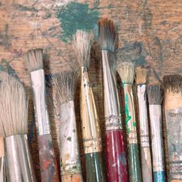 Verschiedene Pinsel liegen auf einem Holztisch.