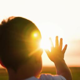Symbolbild:EIn kleines Kind streckt die Hand Richtung untergehender Sonne zu.(Quelle:imago images/Pond5 Images)
