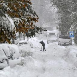 Ein Mann schaufelt Schnee auf einer Straße.