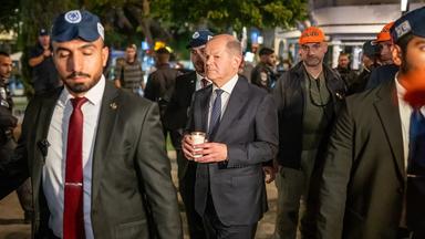 Olaf Scholz steht, umringt von Bodyguards, mit einer Kerze in der Hand am Dizengoff Square im Zentrum von Tel Aviv.