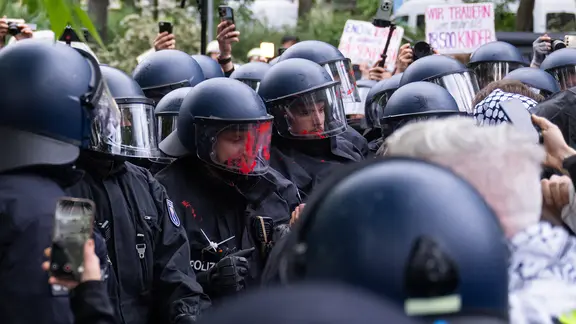 Ein Polizist hat während einer pro-palästinensischen Demonstration am 77. Nakba-Tag rote Farbe auf seinem Visier. | picture-alliance/dpa Ein Polizist hat während einer pro-palästinensischen Demonstration am 77. Nakba-Tag rote Farbe auf seinem Visier.