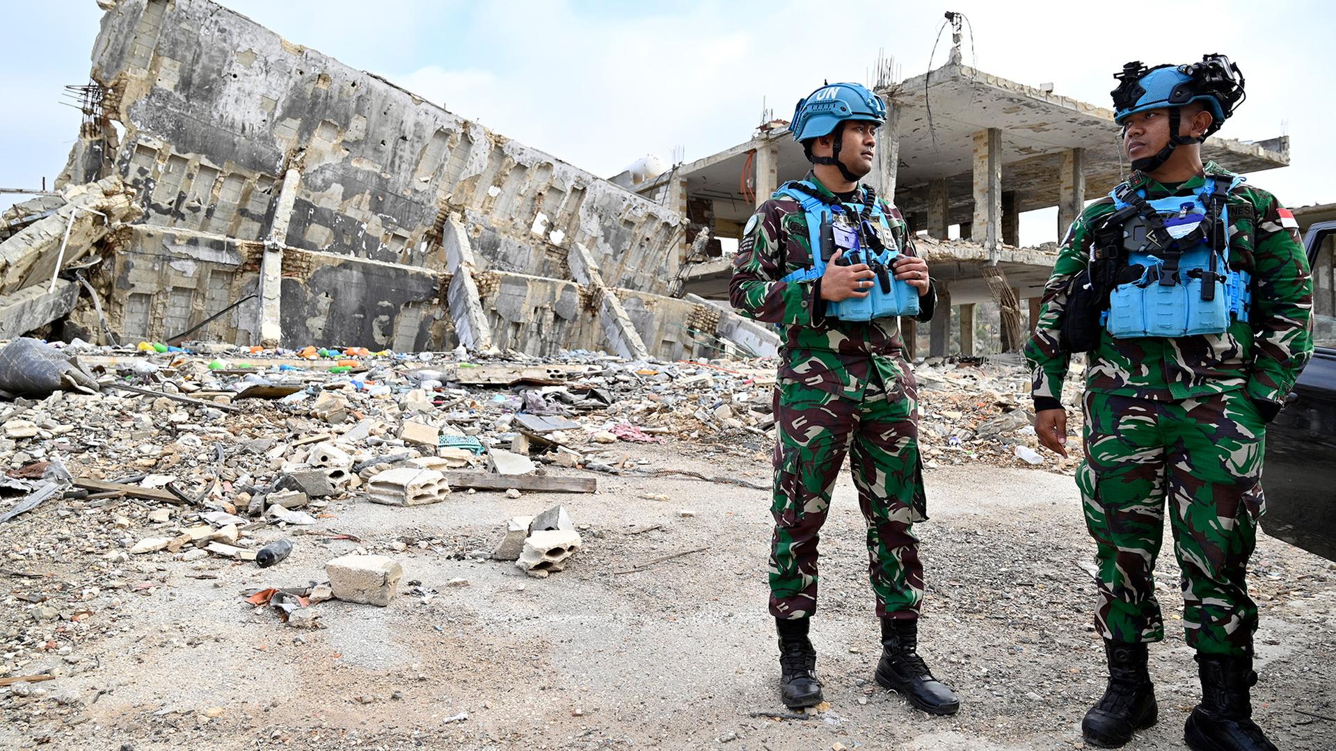 Soldaten der UN Peace Keepers stehen vor zerstörten Gebäuden. | EPA