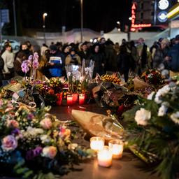 Menschen trauern vor Kerzen und Blumen in Crans-Montana