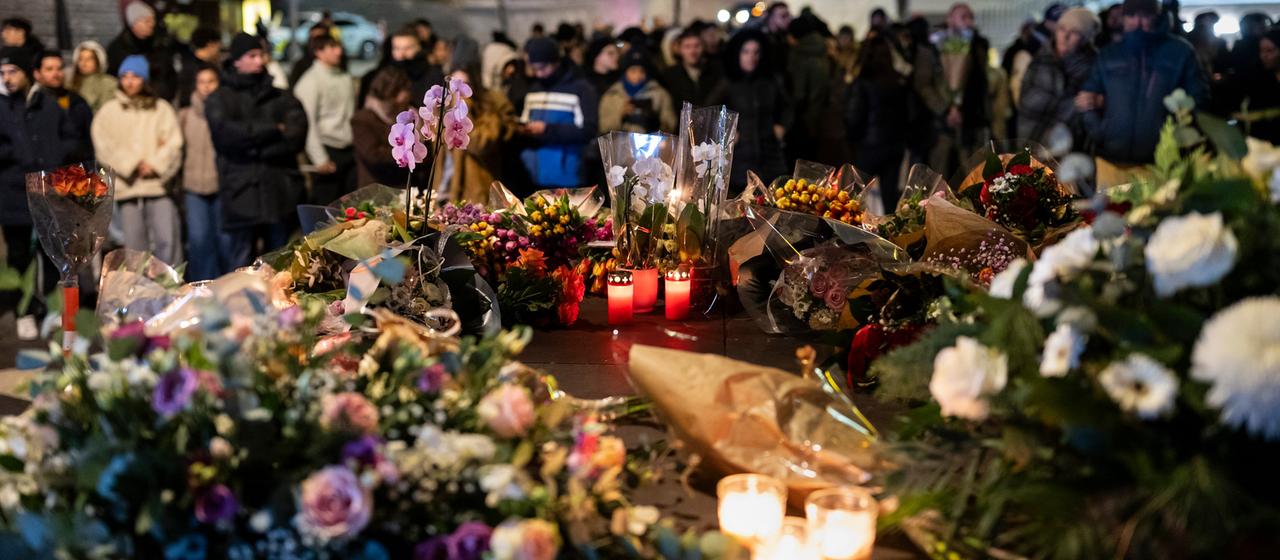 Menschen trauern vor Kerzen und Blumen in Crans-Montana