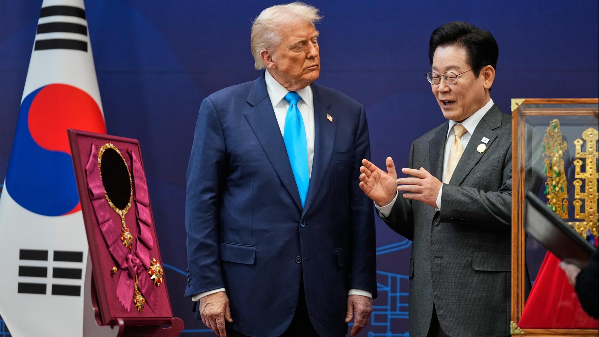 Donald Trump schaut Lee Jae Myung an, neben den beiden steht der höchste Verdienstorden Südkoreas. | dpa