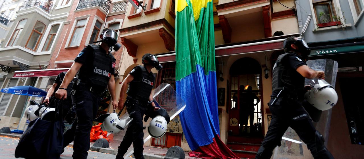 Bereitschaftspolizei  ist in Istanbul vor einer Regenbogenfahne zu sehen.