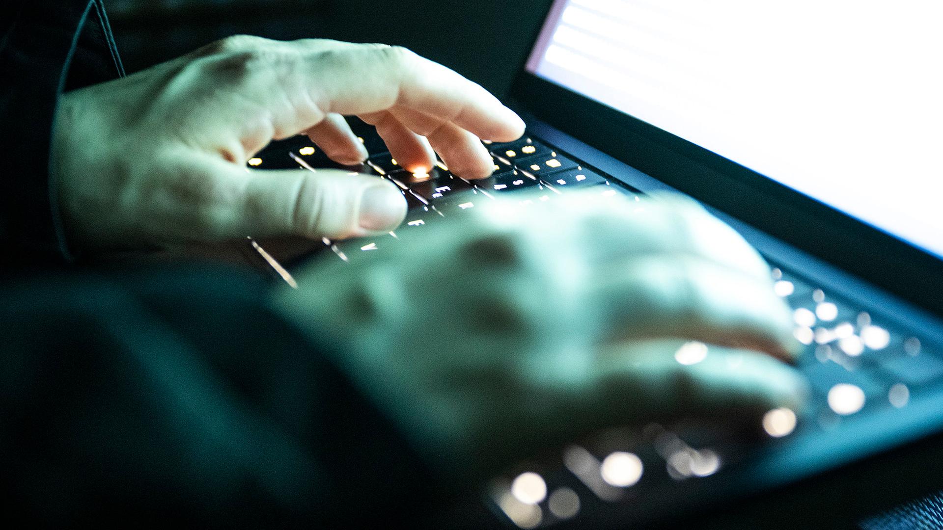 Eine Person tippt mit den Fingern auf einer beleuchteten Laptop-Tastatur. | dpa