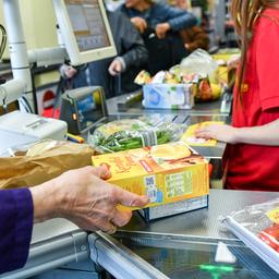 Eine Kundin nimmt in einem Supermarkt Waren vom Band an der Kasse.