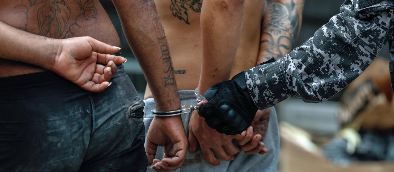 Zwei Männer werden von brasilianischen Polizisten während einer Razzia gegen die Bande Comando Vermelho in Handschellen abgeführt.