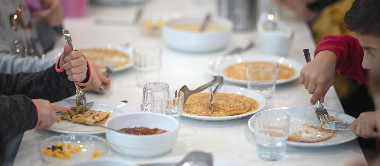 Kinder essen in der Kantine einer Grundschule Mittag.