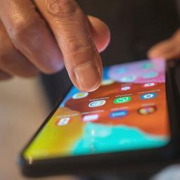 Die Hand eines Seniors tippt auf seinem Smartphone, um eine App zu starten.