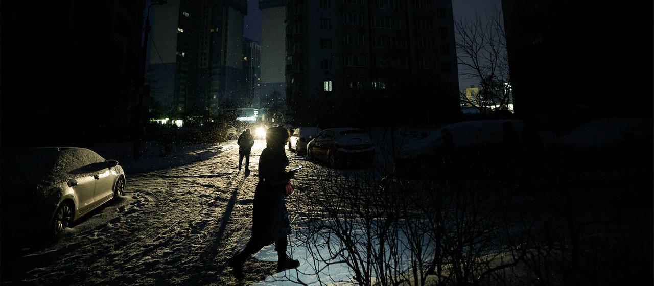 Menschen gehen mit auf einer dunklen Straße während eines Stromausfalls in Kiew.